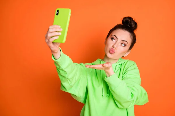Bilde av søt jente som sender luftkyss og tar selfie isolert på livaktig oransje bakgrunn – stockfoto