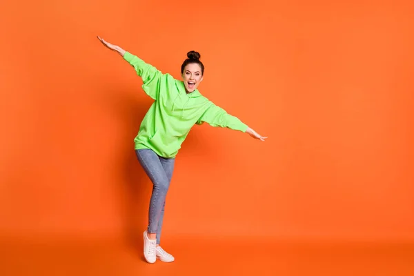 Portrait photo vue complète du corps d'une fille ludique écartant les bras comme un avion riant isolé sur fond orange vif — Photo