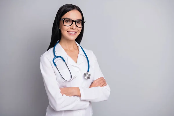 Foto von entzückenden positiven Frau Therapeutin gekleidet weiße einheitliche Brille Arme überquert leeren Raum isoliert graue Farbe Hintergrund — Stockfoto