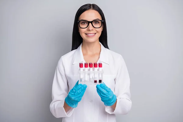 Φωτογραφία της γιατρού κυρία κατέχουν εργαστηριακά δείγματα φορούν γάντια γυαλιά στηθοσκόπιο λευκό ομοιόμορφη απομονωμένο γκρι φόντο χρώμα — Φωτογραφία Αρχείου
