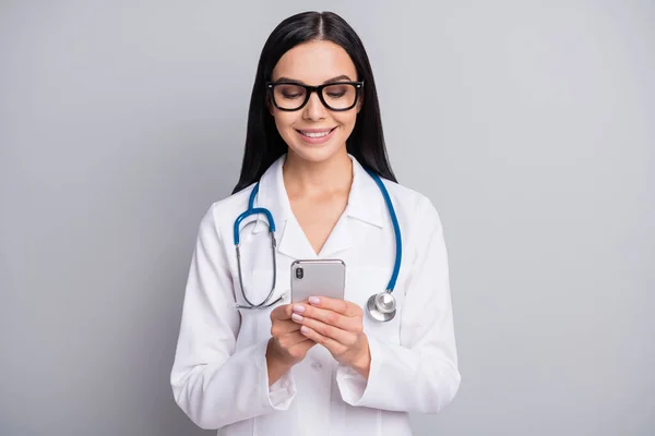 Foto von Arzt Dame halten Telefon-Look Bildschirm tragen Stethoskop-Brille weiß einheitlich isoliert graue Farbe Hintergrund — Stockfoto