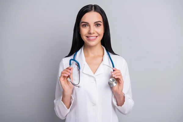 Zdjęcie wesoły lekarz dziewczyna trzymać sprzęt toothy uśmiech nosić stetoskop biały mundur odizolowany szary kolor tło — Zdjęcie stockowe