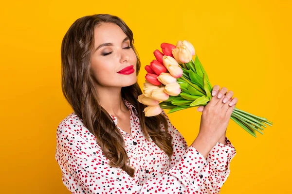 Foto van dromerig geïnspireerd meisje houden bos tulpen gesloten ogen geur slijtage hart print shirt geïsoleerde gele kleur achtergrond — Stockfoto