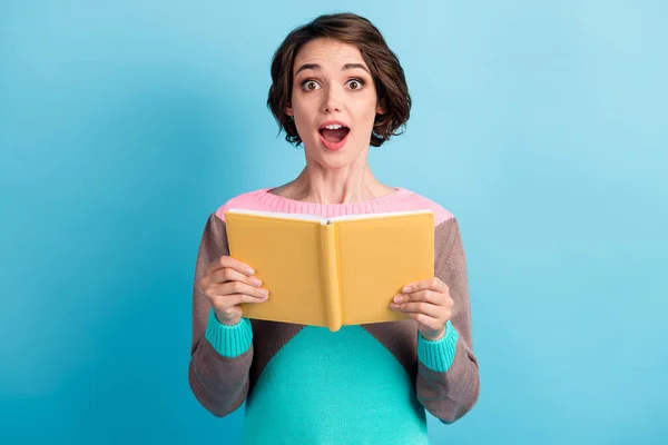 Foto portrét ohromený překvapená školačka zírá s otevřenými ústy vedení žluté knihy izolované na pulzující barvy modrého pozadí — Stock fotografie