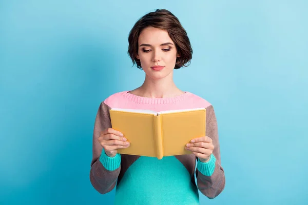 Foto retrato de niña inteligente sosteniendo libro amarillo en dos manos aisladas sobre fondo de color azul claro pastel —  Fotos de Stock