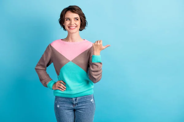 Foto retrato de mulher apontando polegar olhando para o espaço em branco com uma mão na cintura isolada em pastel luz azul colorido fundo — Fotografia de Stock