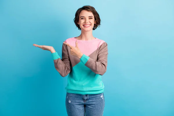 Foto retrato de mulher apontando com o dedo segurando no espaço em branco mão isolado no fundo de cor azul claro pastel — Fotografia de Stock