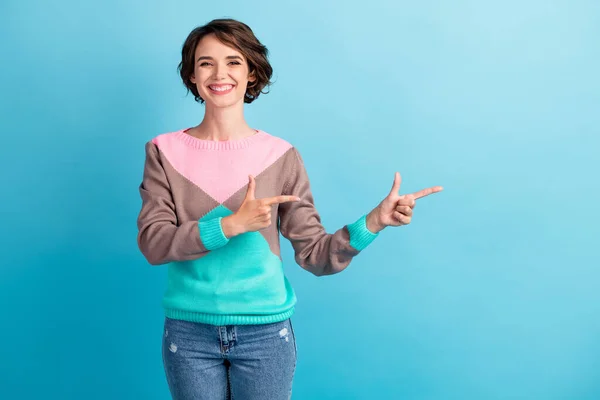 Фотопортрет щасливої жінки, що вказує на два пальці на порожньому просторі, посміхаючись, ізольований на пастельному світло-блакитному фоні — стокове фото