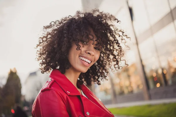 Foto van charmante schattige zoete krullende vrouw gekleed rood jacked lopen straat glimlachen buiten stedelijke stad straat — Stockfoto