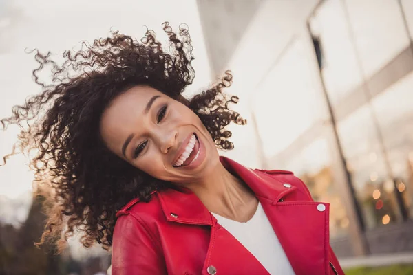 Foto de encantadora senhora ondulada doce usar casaco vermelho sorrindo vento soprando cachos fora da rua urbana da cidade — Fotografia de Stock