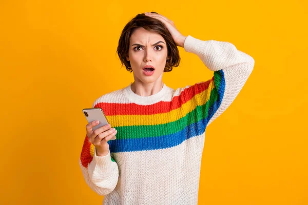 Foto van verwarde meisje houden telefoon hand hoofd staren camera open mond slijtage gestreepte trui geïsoleerde gele kleur achtergrond — Stockfoto