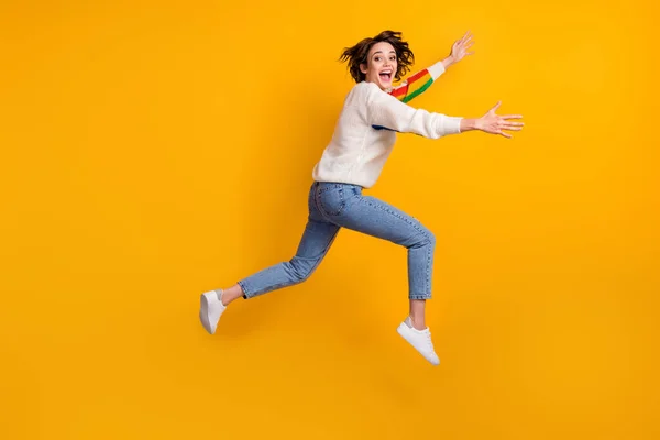 Profiel full size foto van optimistisch grappig meisje run knuffel vriend dragen regenboog trui denim jeans witte schoenen geïsoleerd op gele achtergrond — Stockfoto