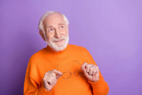 Foto de alegre homem idoso braços segurar óculos olhar interessado espaço vazio imaginar isolado em fundo cor violeta — Fotografia de Stock