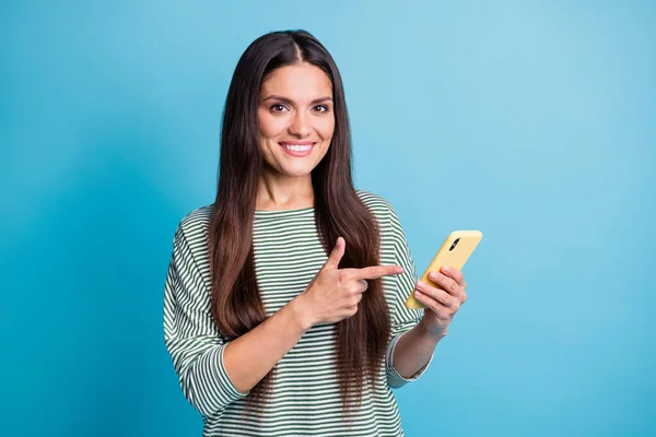Портрет чарівної веселої леді вказує пальцем на порожній простір телефону зубна посмішка ізольована на синьому кольоровому фоні — стокове фото