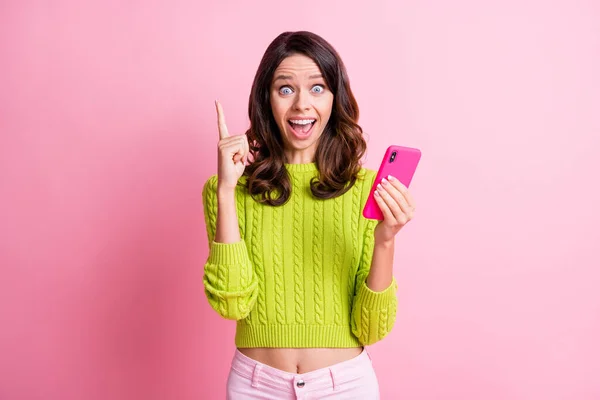 Foto de menina criativa animado segurar telefone boca aberta dedo direto desgaste verde pulôver isolado cor rosa fundo — Fotografia de Stock