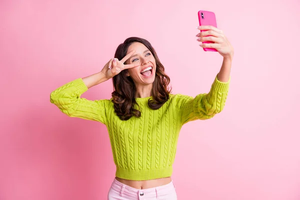 Foto di funky signora tenere cellulare sparare selfie spettacolo v-segno vicino usura occhio verde maglione isolato colore rosa sfondo — Foto Stock