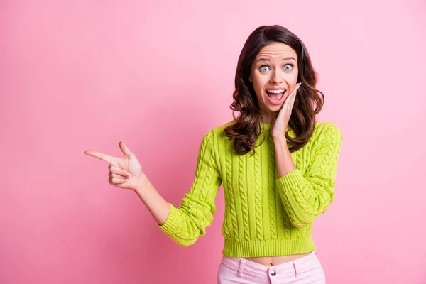 Foto de chica loca palma pómulo boca abierta indican dedo espacio vacío desgaste suéter verde aislado color rosa fondo —  Fotos de Stock