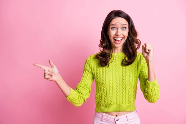 Foto de la señora excitada levante el puño dedo índice directo espacio vacío desgaste suéter verde aislado color rosa fondo —  Fotos de Stock