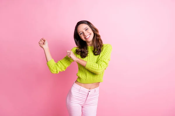 写真のファンキーな陽気な若い女の子のダンスを上げる拳見てカメラは緑のプルオーバー孤立ピンク色の背景を着用 — ストック写真