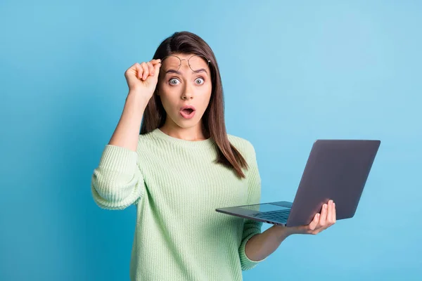 Foto av förvånad flicka hålla laptop höja glasögon stirra i kameran dumdristigt isolerad över blå färg bakgrund — Stockfoto