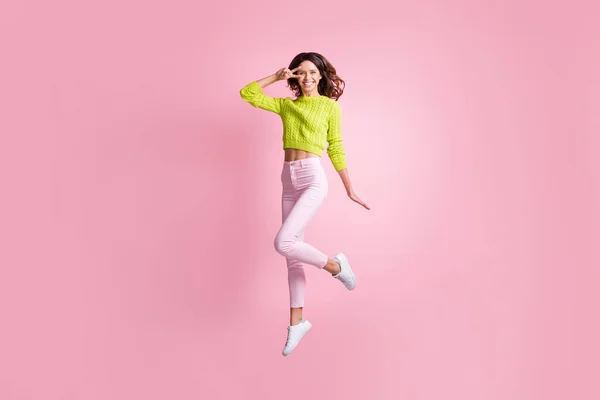 Pełna długość zdjęcie cute girl jump show v-znak nosić zielony sweter spodnie obuwie odizolowany różowy kolor tło — Zdjęcie stockowe