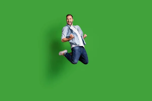 Full size foto di hooray divertente ragazzo saltare urlare indossare camicia blu jeans calzature isolate su sfondo di colore verde — Foto Stock