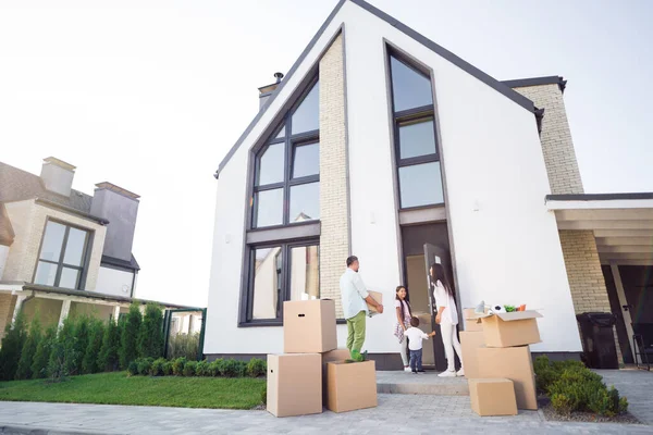 Fotoporträt einer großen Familie beim Umzug ins neue Haus Vater bringt alles rein, Schwester führt Bruder und Mutter hält Tür draußen — Stockfoto