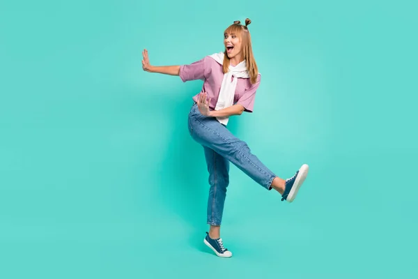Omuzlarında kazakla turkuaz renkli arka planda dans eden mutlu ve mutlu bir genç kızın tam boy fotoğrafı. — Stok fotoğraf