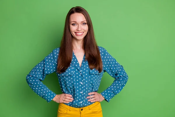 Porträt von attraktiven fröhlichen zufriedenen Mädchen trägt gepunktete Bluse Hände auf Hüften isoliert über leuchtend grünen Farbhintergrund — Stockfoto