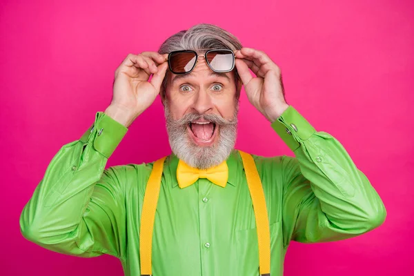 Closeup photo of crazy trendy clothes aged grandpa positive news good mood sale shopping wear sun specs green shirt yellow suspenders bow tie isolated vivid pink color background — Stock Photo, Image