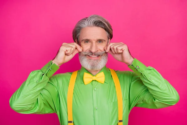Foto de divertido abuelo de moda astuta expresión facial rizado bigote ideal guapo tipo usar camisa verde tirantes amarillos pajarita aislado vívido color rosa fondo —  Fotos de Stock