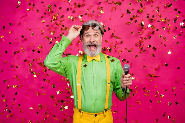 Bedava alkol. Komik büyükbaba partisinin fotoğrafı. Karaoke mikrofonu söylerken heyecanlanıyor. Güneş gözlüklerini çıkarırken yeşil gömlek giyiyor. — Stok fotoğraf