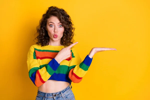 Foto de chica bastante divertida indican brazo dedo índice mantenga los labios vacíos desgaste jersey de rayas aislado color amarillo fondo — Foto de Stock