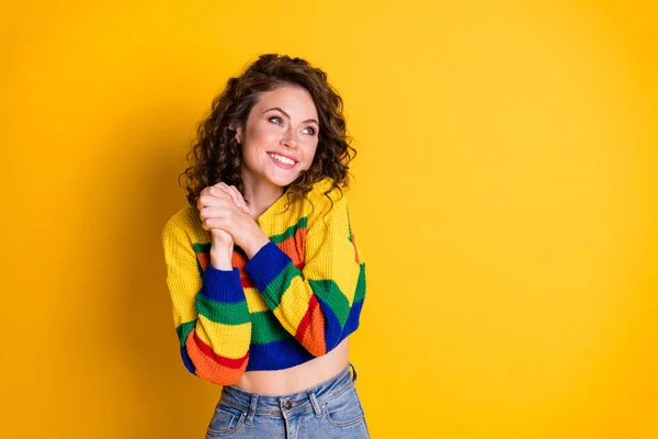 Фото очаровательной девушки держатся за руки смотреть на пустое пространство блестящая улыбка носить полосатый обрезанный пуловер изолированный желтый цвет фона — стоковое фото