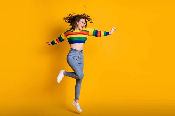 Foto de comprimento total de mulher salto encantador vestido casual camisola colorida dançando apontando para o espaço vazio isolado cor amarela fundo — Fotografia de Stock