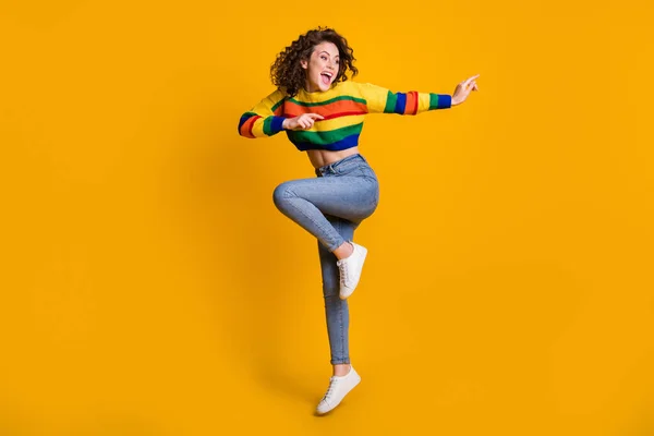 Foto de longitud completa de la señora saltando con suéter colorido casual bailando apuntando buscando espacio vacío de pie una pierna aislado color amarillo fondo — Foto de Stock
