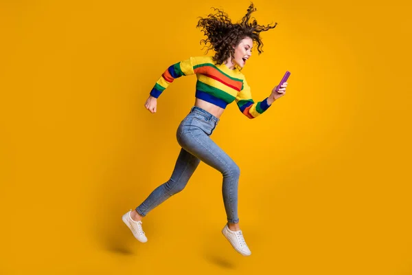 Perfil de tamaño completo foto de alegre bastante ondulado pelo chica ejecutar leer mensaje usar suéter jeans zapatillas aisladas sobre fondo amarillo — Foto de Stock