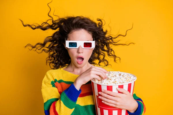 Photo of surprised funky young brunette lady hold popcorn watch movie wear spectacles sweater isolated on yellow color background — Stock Photo, Image