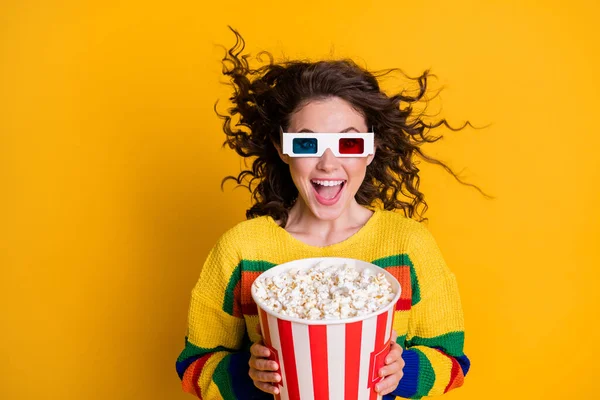 Photo of amazed funky young brunette hair lady hold popcorn watch film wear spectacles bright sweater isolated on yellow color background