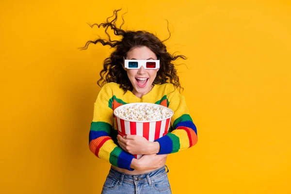 Foto av förvånad funky ung brunett hår dam hålla popcorn titta på tv bära glasögon tröja jeans isolerad på gul färg bakgrund — Stockfoto