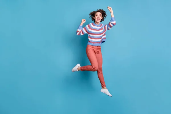 Tamanho do corpo de comprimento total foto de saltar alegremente jovem gestos como vencedor isolado no fundo de cor azul vívido — Fotografia de Stock