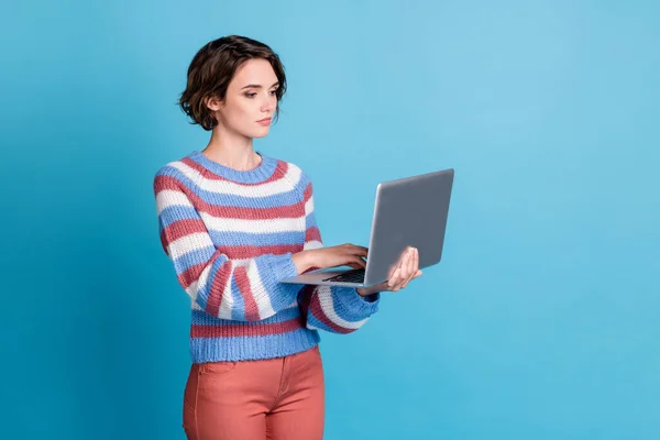 Retrato fotográfico de una freelancer femenina seria y concentrada que utiliza Internet para mantener la navegación por ordenador portátil aislada sobre un fondo de color azul brillante — Foto de Stock