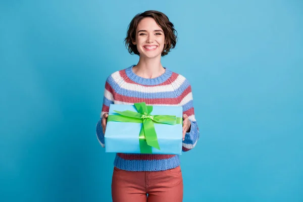 Foto portrét veselá dívka vedení dárek k narozeninám na sobě ležérní svetr izolované na pulzující modré barvy pozadí — Stock fotografie