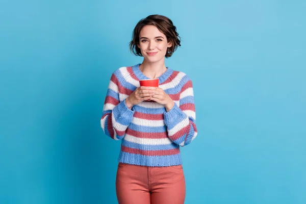 Фотопортрет милої усміхненої дівчини, що тримає червоний кухоль в повсякденному одязі ізольовано на яскраво-блакитному фоні — стокове фото