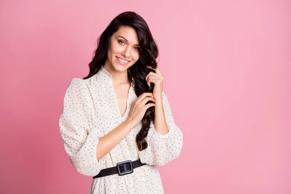 Foto retrato de menina sonhadora tocando seda morena longo ondulado cabelo sorrindo isolado pastel cor de fundo rosa com espaço em branco — Fotografia de Stock