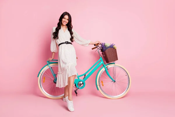 Foto de cuerpo entero del tamaño de la muchacha bonita que está parada con la bicicleta azul en vacaciones aisladas en fondo de color rosa pastel — Foto de Stock