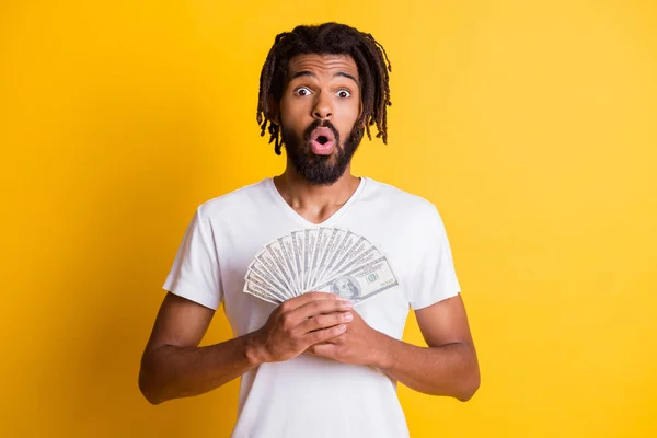 Photo of young black shocked guy hold salary cash fan wear white t-shirt isolated yellow color background — Stock Photo, Image