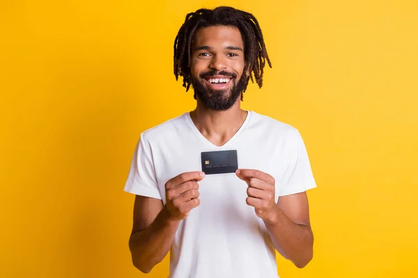 Fotografie de tip negru hold demonstra cardul de debit arata camera purta alb t-shirt izolat galben culoare fundal — Fotografie, imagine de stoc