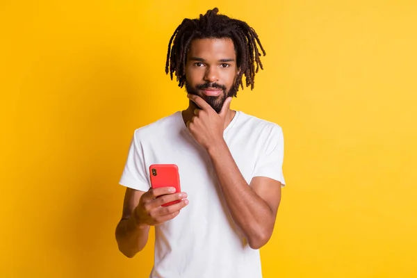 Photo de l'étudiant intelligent peau foncée gars tenir bras de téléphone sur le menton ont belle idée porter t-shirt isolé couleur jaune fond — Photo