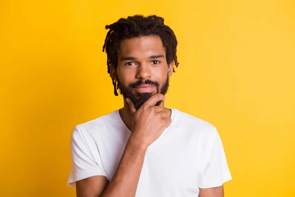 Foto de pele escura inteligente cara olhar câmera segurar braço no queixo desgaste casual t-shirt isolado cor amarela fundo — Fotografia de Stock